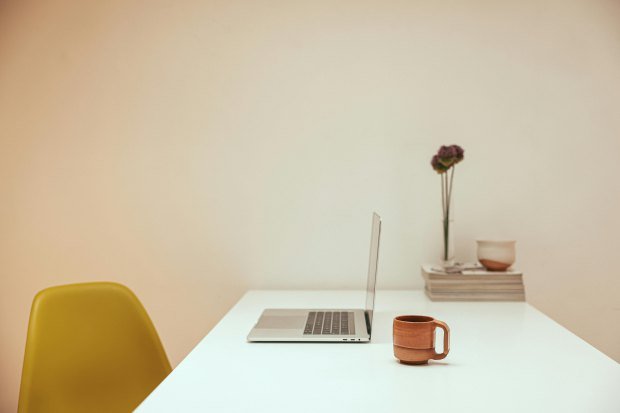 A serene minimalist workspace featuring a laptop and coffee on a white desk.