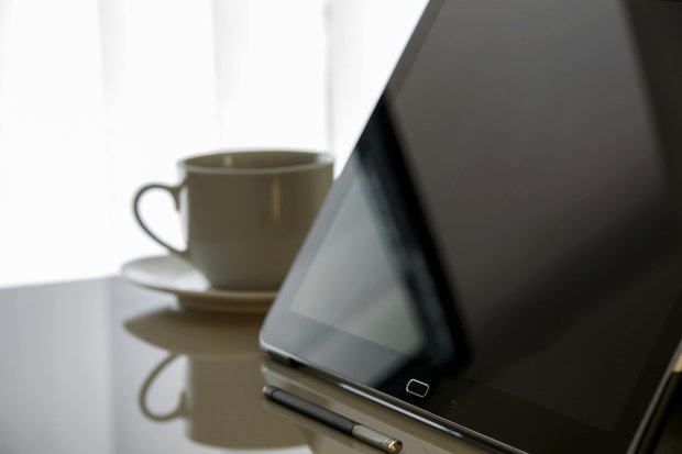 Modern tablet and coffee cup on a reflective desk, perfect for tech-related content.